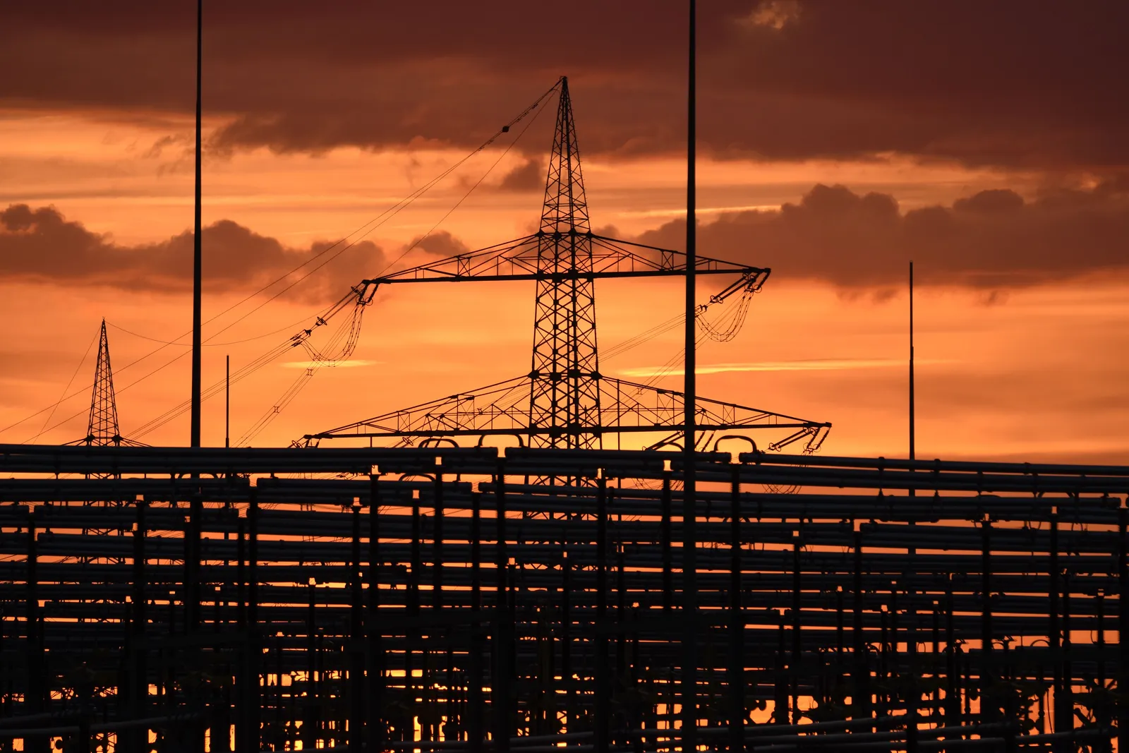 Hoogspanningsleidingen boven industriële installaties bij zonsondergang